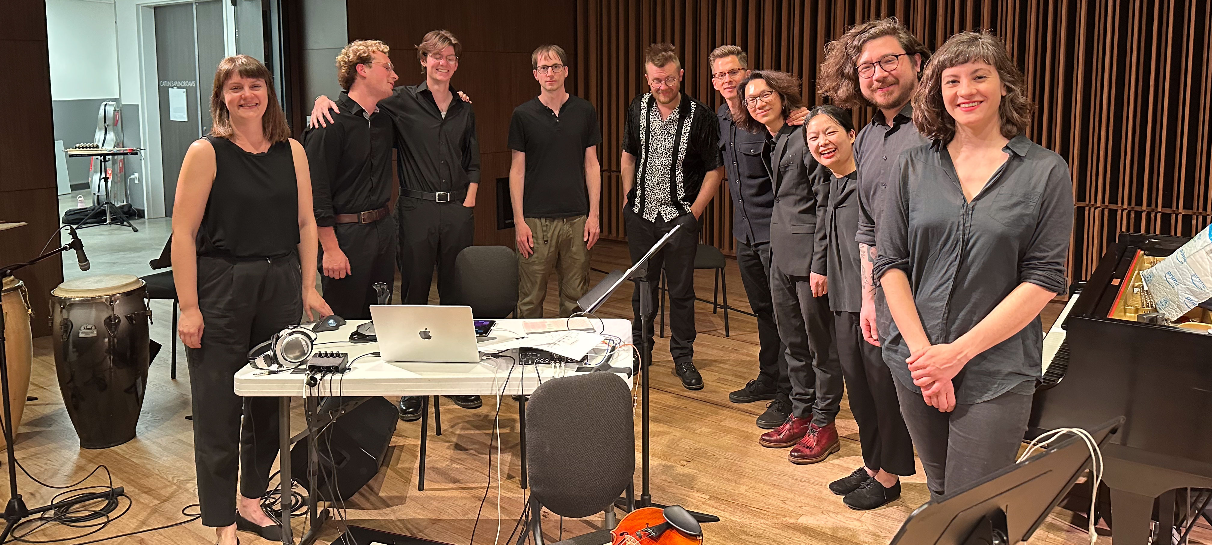 Ensemble Pink Noise after a concert smiling on a wooden stage with microphones and a piano.