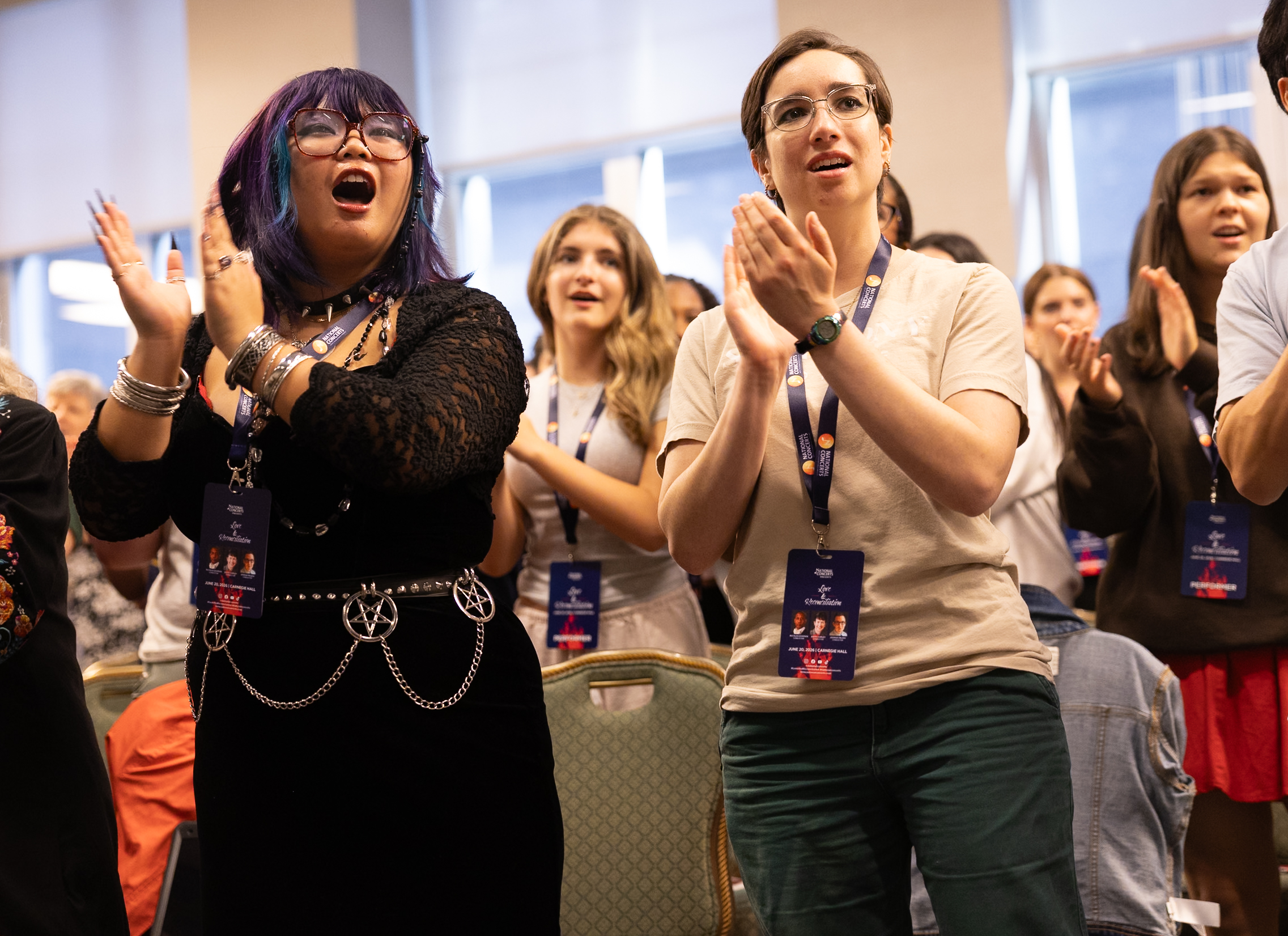Group of conference attendees standing and applauding, smiling and wearing lanyards