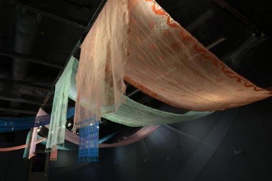 Translucent fabric panels draped from ceiling, lit with soft teal and orange lights