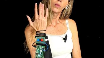 Middle-aged woman holding a DIY electronic wrist device against black background