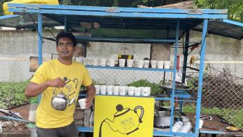 Man in yellow shirt pouring tea at mobile chai cart with Chai Stories logo