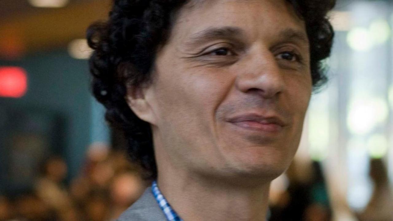 Portrait of Juan Diego Díaz outdoors, wearing a gray suit jacket and looking off to the side with a slight smile.
