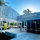 Gorman Museum entrance with glass facade and white ornate canopy under blue sky