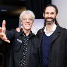 Composer Stewart Copeland stands left with an outstretched arm towards the camera, with Jeremy Borum, right, both smiling.