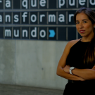 TV video still showing a woman speaking, with the Spanish-language text "transformar el mundo" overlaid on the frame.