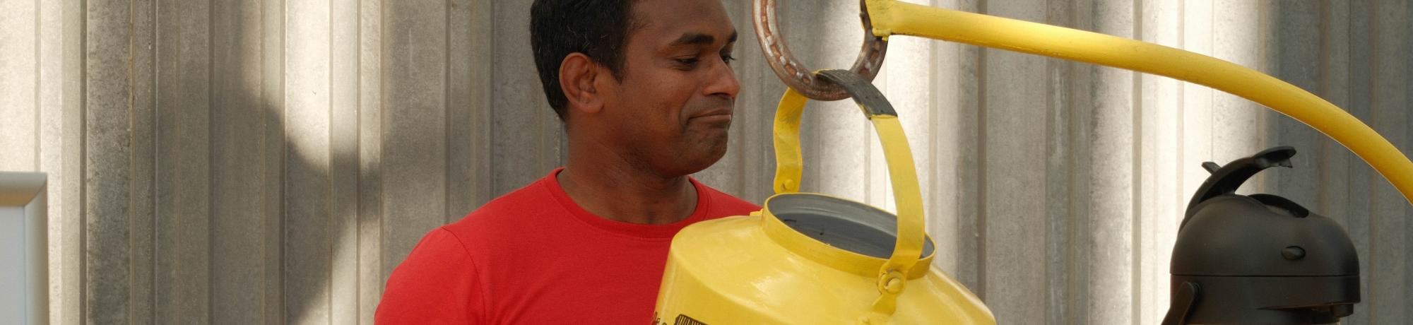 Man in red shirt behind yellow coffee cart with vintage percolator and thermos