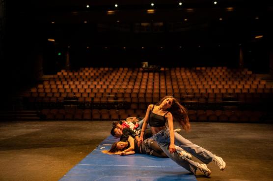 Student in motion falling to mat on floor with cast members behind them
