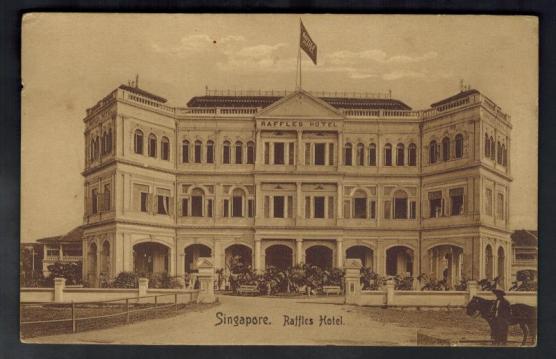 A scanned sepia-tone postcard of a three story hotel with a flag on the roof at center.