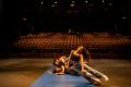Student in motion falling to mat on floor with cast members behind them